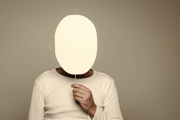 man with paper nameplate hiding face on grey background - 写真・画像