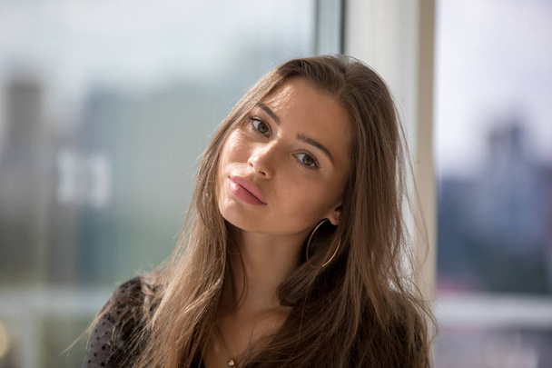 Portrait of an attractive girl on a window background. - Fotografie, Obrázek