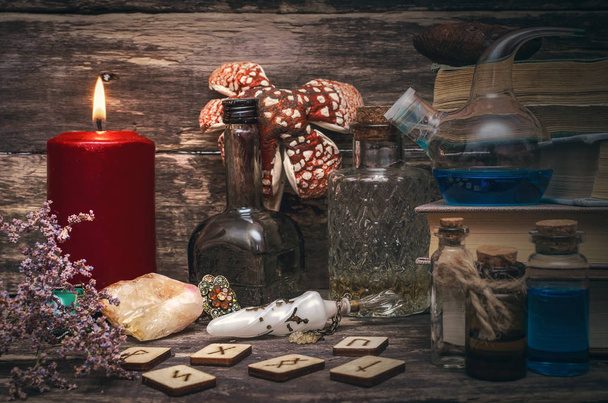Magic potion, runes for divination and stack of old books on the magician table. Witchcraft concept. - Φωτογραφία, εικόνα