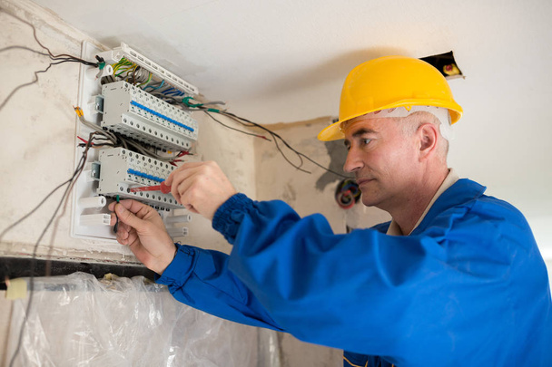 Senior electrotechnician connecting wiring system and completing the preparation of the electrical circuit home network - Foto, Imagem