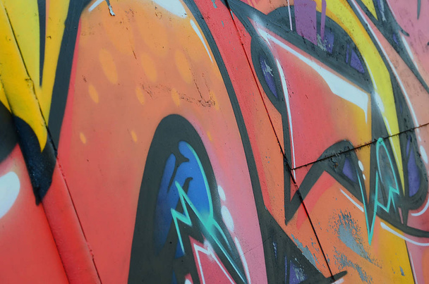 Фрагмент граффити рисунков. Старая стена декорирована краской в стиле уличного искусства. Цветная текстура фона в теплых тонах
. - Фото, изображение