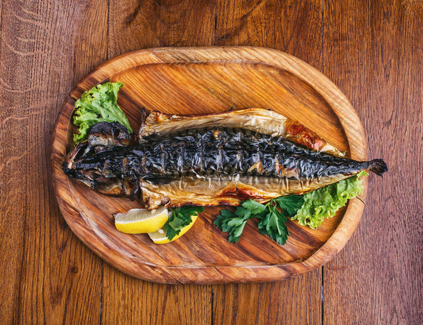 Plat de poisson avec différents ingrédients sur une assiette en bois
 - Photo, image