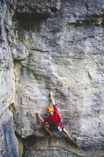 A man in helmet climbs the rock. Climbing in nature. Fitness outdoors. Active lifestyle. Extreme sports. The athlete trains on a natural relief. Rock climbing in Ukraine. - Photo, Image