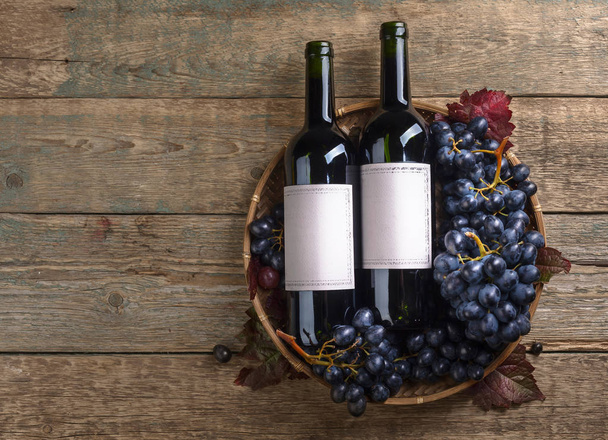 Grapes and bottles of red wine on a old wooden background. Old paper label , copy space for your text. Top view . - Photo, Image