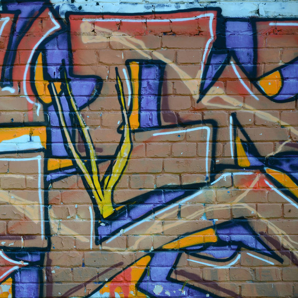 Fragment van graffiti tekeningen. De oude muur versierd met verf vlekken in de stijl van straatkunst cultuur. Gekleurde achtergrond textuur in warme tinten. - Foto, afbeelding
