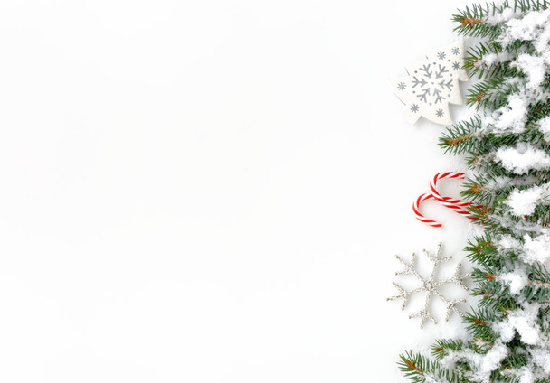 Doğal köknar ağacı twigs, beyaz Noel ağacı süsleme, beyaz gümüş Noel yıldız süs ve iki kırmızı ve beyaz çizgili şeker köpekler Noel sınır kar ile kaplı.  - Fotoğraf, Görsel