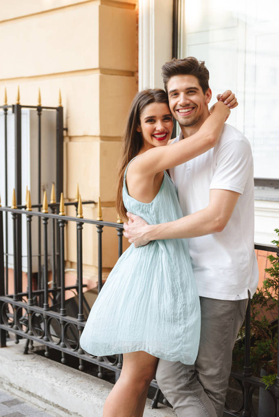 Happy young couple hugging at the city street, looking at camera - Фото, зображення