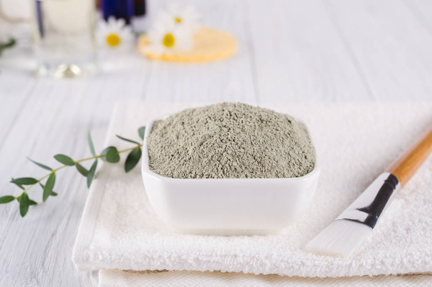 Preparing cosmetic mud mask with various skincare products. Dry clay powder in bowl. Natural cosmetics for home or salon spa treatment. On white background. - Photo, Image