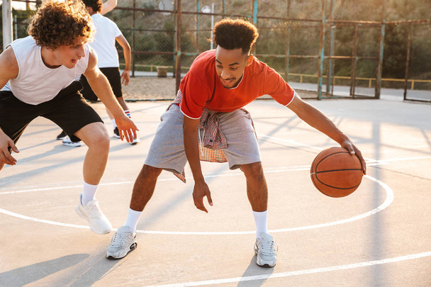 Portrait of athletic american and caucasian men playing basketball at the playground outdoor during summer sunny day - Fotoğraf, Görsel