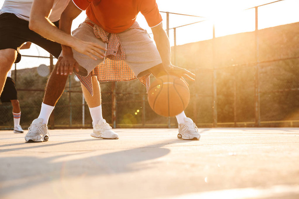 Cropped image of multiethnic men basketball players playing basketball at the sport ground - Foto, imagen