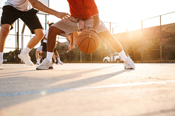 Cropped image of strong multiethnic men basketball players playing basketball at the sport ground - Foto, immagini