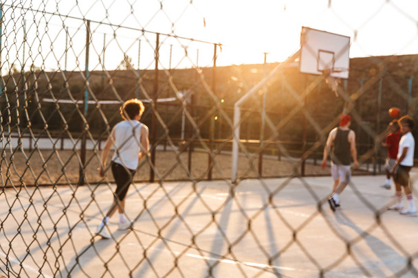Group of young cheerful multiethnic men basketball players playing basketball at the sport ground - Foto, immagini