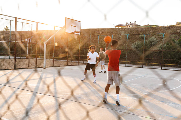 Group of young multiethnic men basketball players playing basketball at the sport ground - Photo, Image