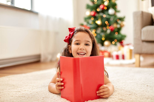 happy girl reading book at home on christmas - Valokuva, kuva