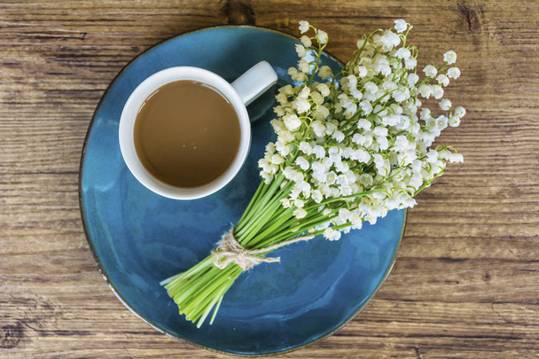Spring Table Setting with Vintage Blue Cutlery and Lily of the Valley Flowers on a Wooden Background.Floral Table Decor with Coffee Cup.Top view - Foto, Bild