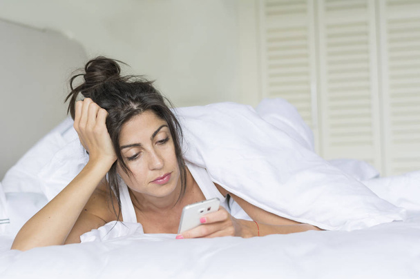 Sad Young Woman Talking on the Phone in the Bed - Foto, Imagen