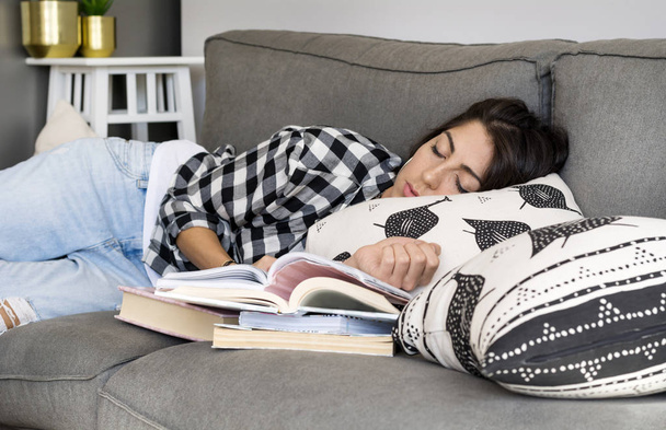 Zmęczony kobiecie spania z książką w rękach na kanapie w salonie - Zdjęcie, obraz