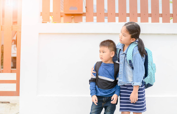 Sister and brother looking school bus in front of home, back to school concept - Photo, Image