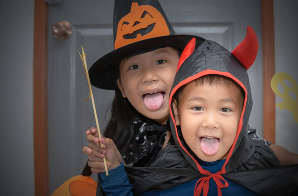 fröhliches Teufelslächeln und süße kleine Hexe, Halloween-Konzept - Foto, Bild