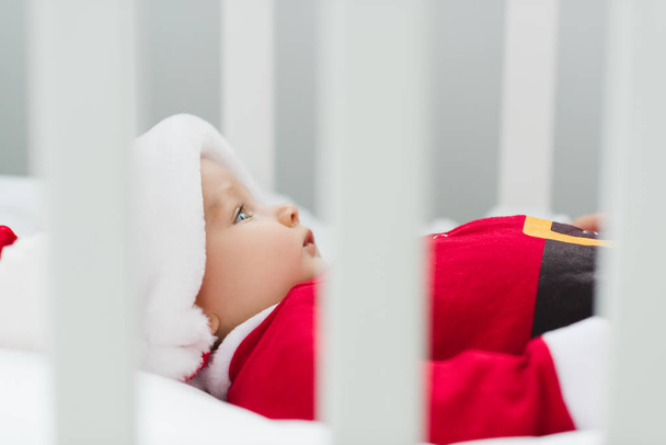 primer plano de lindo bebé en traje de santa acostado en cuna
 - Foto, Imagen
