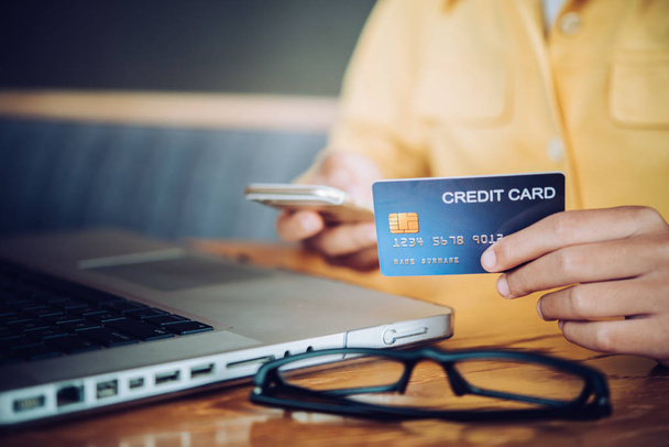 Bir kredi kartı onların elinde tutan el ve çevrimiçi alışveriş yapmak ve mali işlemleri için kendi dizüstü aygıtı kullanarak bir ürün hakkında bilgi. - Fotoğraf, Görsel