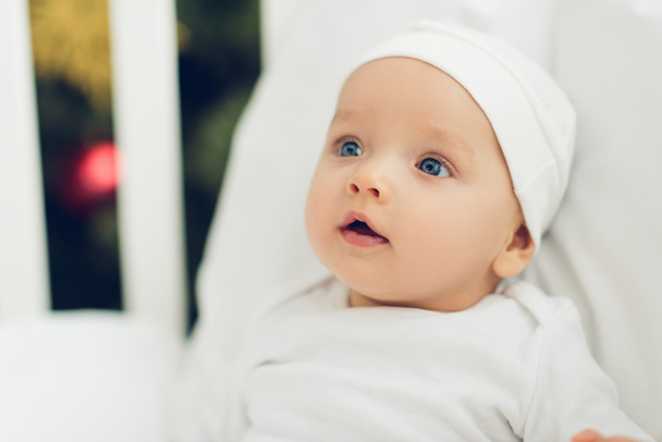 retrato de cerca de adorable bebé en sombrero blanco mirando hacia otro lado
 - Foto, Imagen