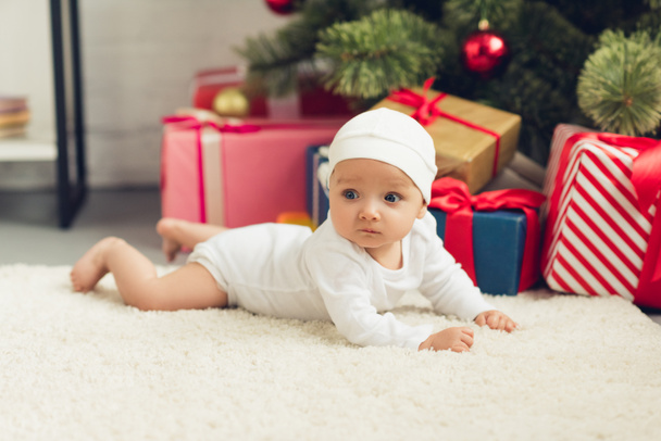 bellissimo piccolo bambino sdraiato sul pavimento con regali di Natale
 - Foto, immagini