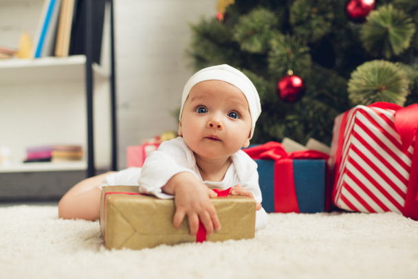 adorable little baby lying on floor with christmas gifts - Foto, Imagen