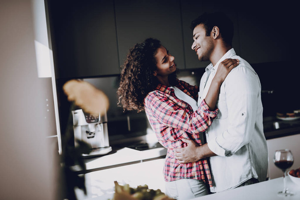 Afro American Couple Is Hanging In Kitchen. Weekend Concept. Holiday Resting. Smiling Together. Having Fun. Romantic Date. Cheerful Sweethearts. Staring At Each Other. Happy Family. - Photo, image