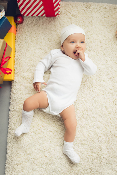 adorable little baby lying on floor with gift boxes - Foto, Bild