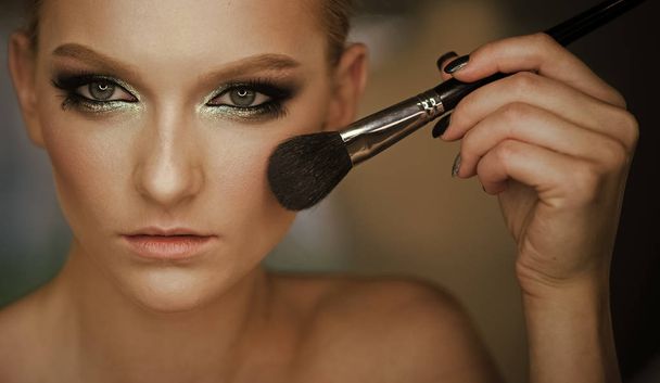 Woman with young face skin in beauty salon. Beauty model apply powder on face, cosmetics. Girl skin, skincare, cosmetics. Visage course and glamour make up. Woman use brush for makeup, visage. - Foto, imagen