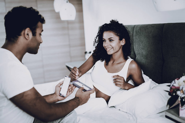 A Man Is Making A Gift To Girlfriend In Bedroom. Love Each Other. Sweetheart's Romantic Moment Concept. Young And Handsome. Happy Relationship. Feelings Showing. Present Giving. Couple Harmony. - Fotoğraf, Görsel