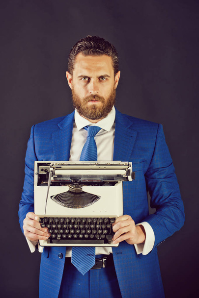 άνθρωπος με γραφομηχανή στην μόδα μπλε επαγγελματικό κοστούμι σε γκρίζο φόντο - Φωτογραφία, εικόνα
