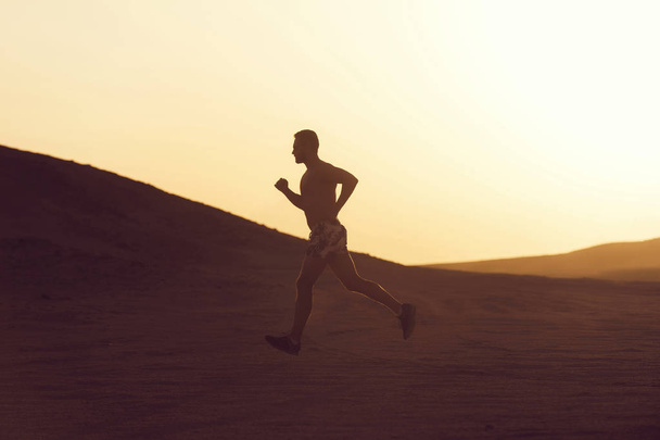 Man runner running in dune at sunset - Photo, image