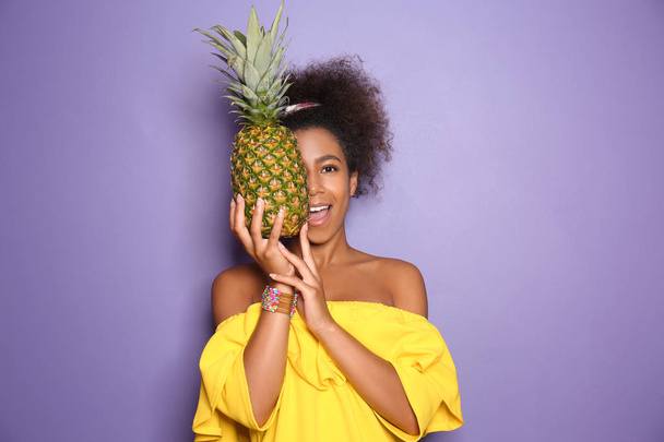 Schöne afroamerikanische Frau mit Ananas auf farbigem Hintergrund - Foto, Bild