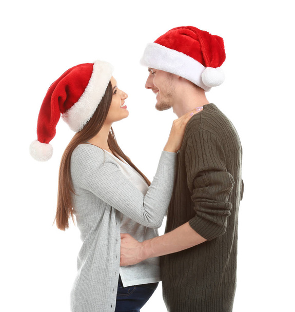 Portrait of cute young couple in Santa hats on white background - Photo, Image