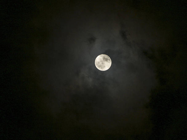 volle maan met wolken rond in tinten van kleuren - Foto, afbeelding