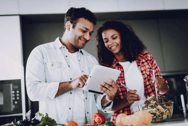 Afro American Happy Couple Cooking At Kitchen. Weekend Concept. Holiday Resting. Smiling Together. Having Fun. Cheerful Sweethearts. Time To Breakfast. Healthy Lifestyle. Tablet Screen. - Photo, Image