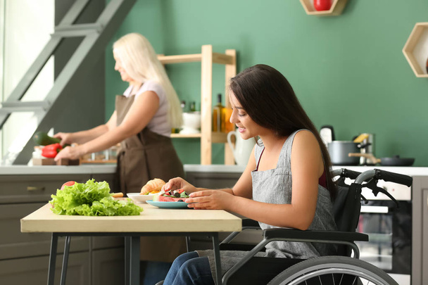 Jonge vrouw in rolstoel eten thuis - Foto, afbeelding
