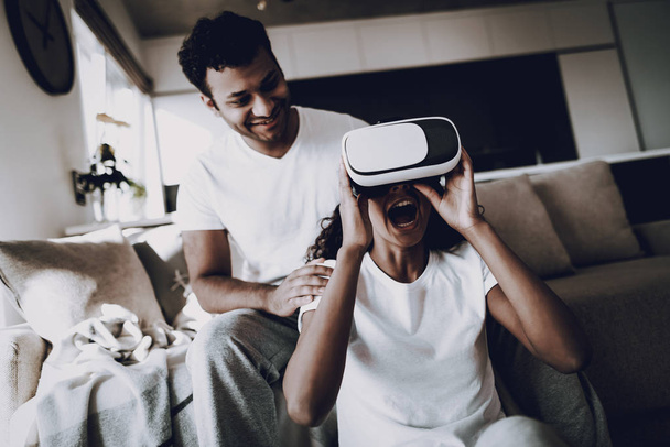 Afro American Couple With Virtual Reality Glasses. Weekend Concept. Morning Leisure. Have A Break. Look On The Screen. Chilling On Sofa. Holiday Resting. Smiling Together. Having Fun. - Foto, Imagen