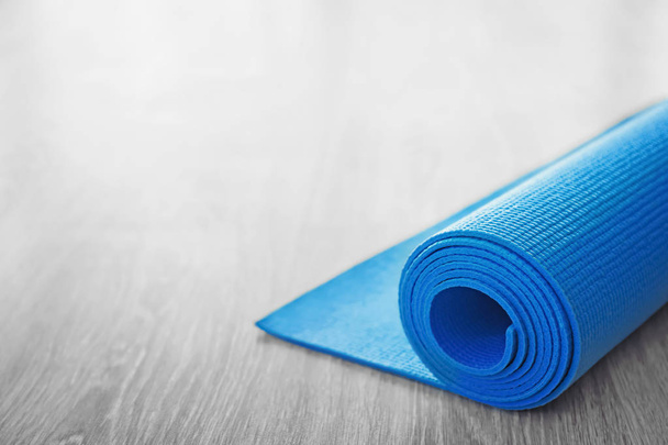 Yoga mat gerold op houten vloer - Foto, afbeelding