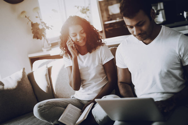 Afro American Couple On Couch. Holiday Concept. Morning Leisure. Have A Break. Look On The Screen. Chilling On Sofa. Weekend Resting. Smiling Together. Hands On Keyboard. Electronic Gadgets. - Foto, imagen