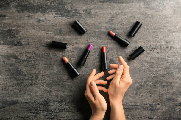Female hands and colorful lipsticks on dark wooden table - Fotó, kép