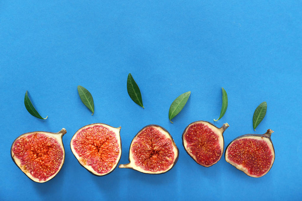 Fresh ripe figs and green leaves on color background, flat lay - Photo, Image