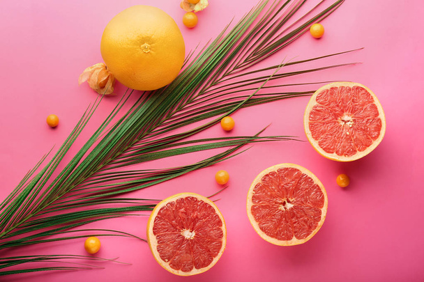 Ripe juicy grapefruits and palm leaf on color background, flat lay - Photo, Image