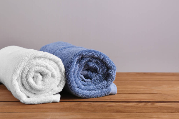 Warmgewalste schone zachte handdoeken op houten tafel - Foto, afbeelding