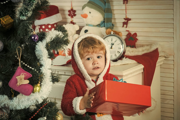 christmas child or small boy in santa coat hold present - Foto, afbeelding