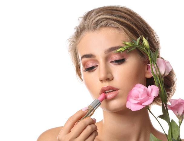 ピンクの口紅と白い背景の花を持つ美しい若い女性 - 写真・画像