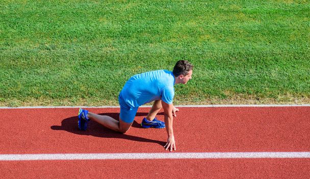 Athlete runner prepare to race. Running tips for beginners. Man athlete stand low start position stadium path. Runner ready to go. Joint mobility exercises to improve flexibility and function - Foto, imagen