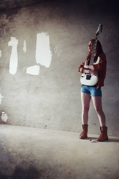 Young red-haired girl with an electric guitar. Rock musician gir - Photo, Image